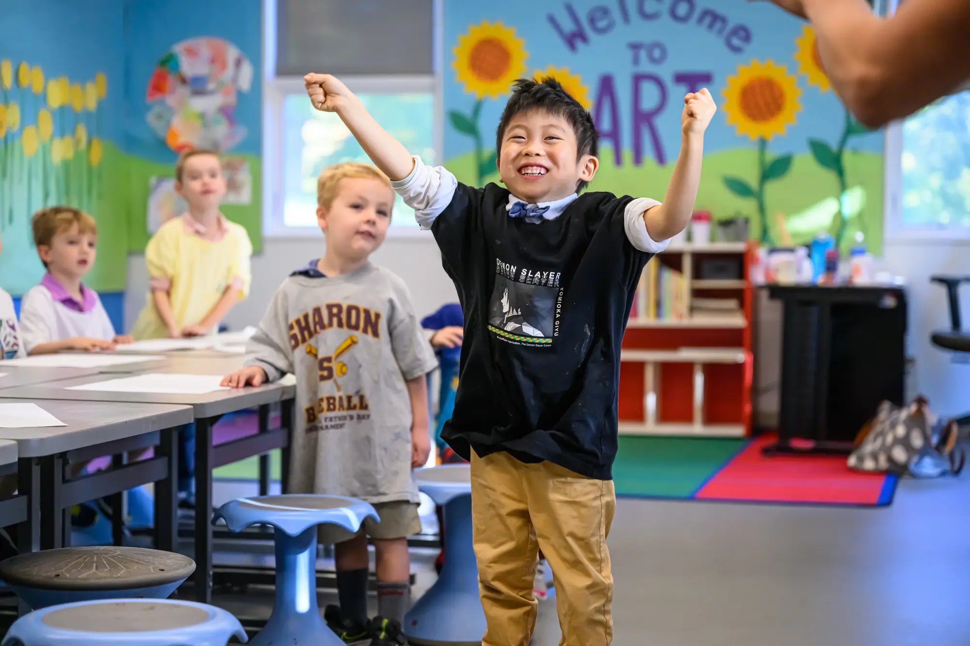Un niño celebra con los brazos en alto en clase