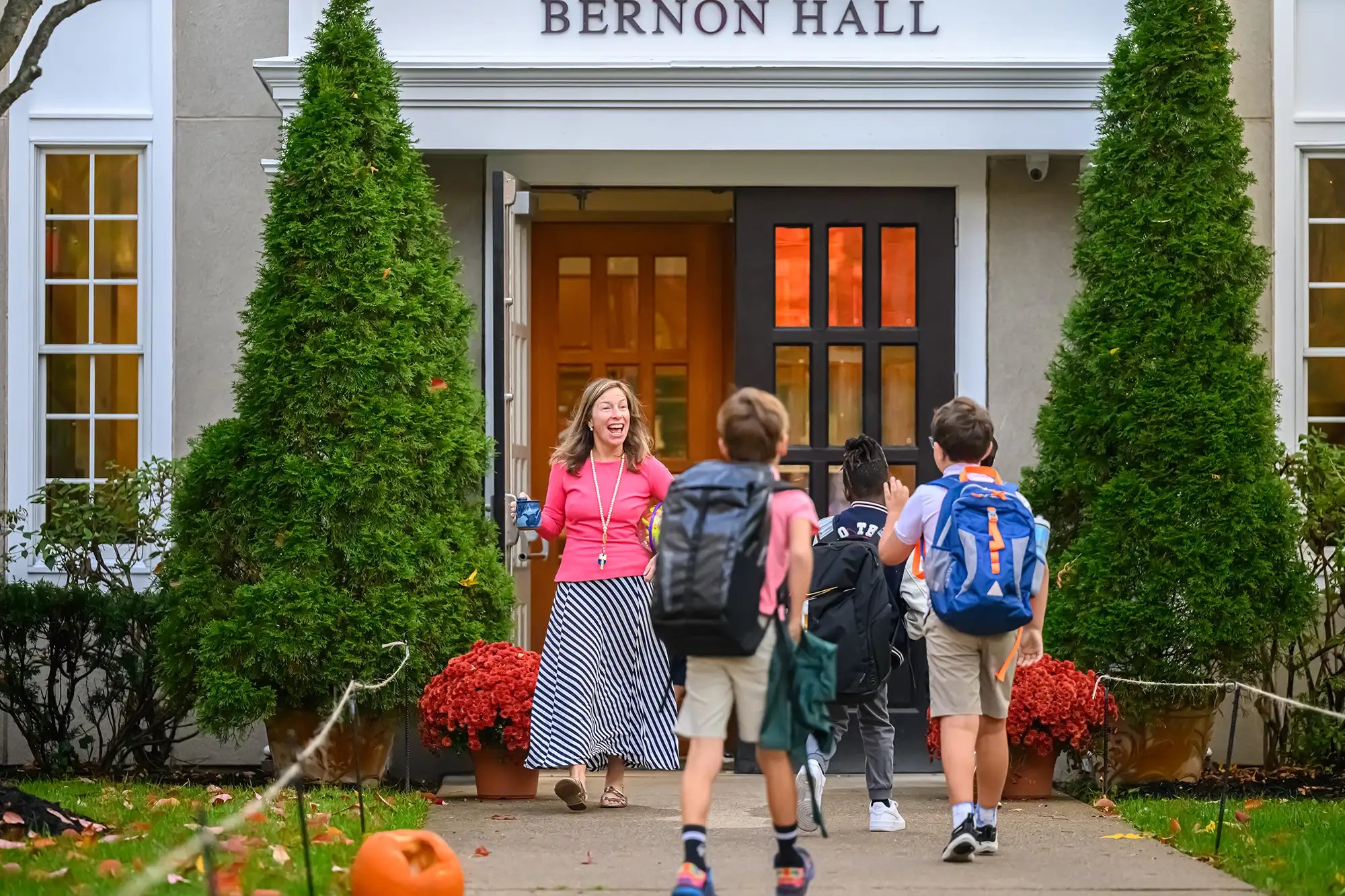 Un profesor saluda a los alumnos en el exterior del Bernon Hall